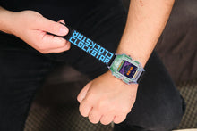Load image into Gallery viewer, A close-up of a person wearing a Casio digital watch with a translucent green and blue strap, while holding the matching branded strap on the other hand.