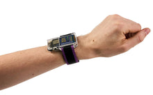 Load image into Gallery viewer, A wrist-mounted electronic device with a clear rectangular face and a black strap featuring purple stripes, shown worn on a person's wrist against a plain white background.