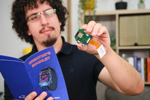 Load image into Gallery viewer, Person holding a small electronic component and a book titled 'Creator's Booklet' in an indoor setting.