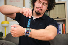 Load image into Gallery viewer, Man wearing a black shirt with text and a vintage-style watch, sitting in a casual indoor setting.