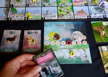 Load image into Gallery viewer, Collection of Good Dog Bad Zombie board game cards with various illustrations and text on a dark surface.