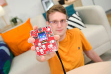 Load image into Gallery viewer, Person holding a red electronic device with a screen in a living room setting
