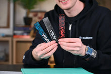 Load image into Gallery viewer, Person holding three USB drives with visible branding in an indoor setting
