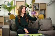 Load image into Gallery viewer, Woman holding a small purple device in a living room setting
