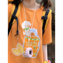 Load image into Gallery viewer, Person wearing an orange shirt with a cartoon design, holding a lanyard with a small device.
