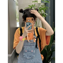 Load image into Gallery viewer, Person taking a mirror selfie with a phone case featuring a cartoon character, wearing an orange shirt and denim overalls.
